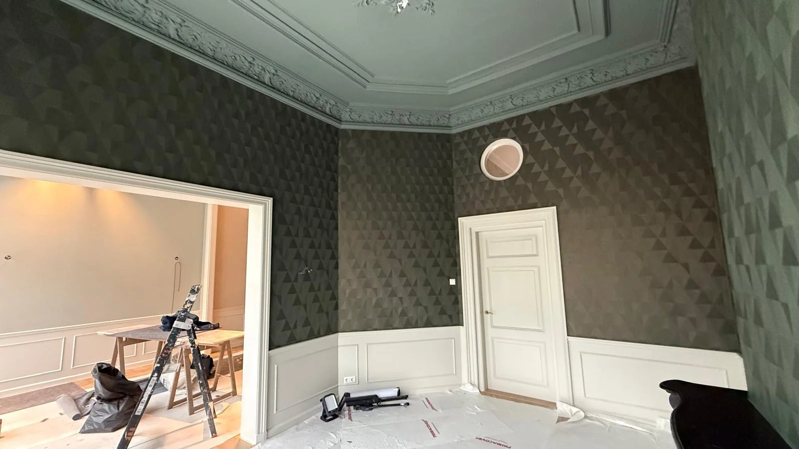 Klassieke kamer met donkere wandbekleding, witte lambrisering en rijk gedetailleerd plafond